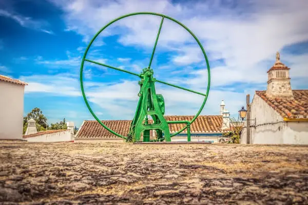 Velik, zelen, okrogel mehanizem z vasjo v ozadju pod modrim nebom.